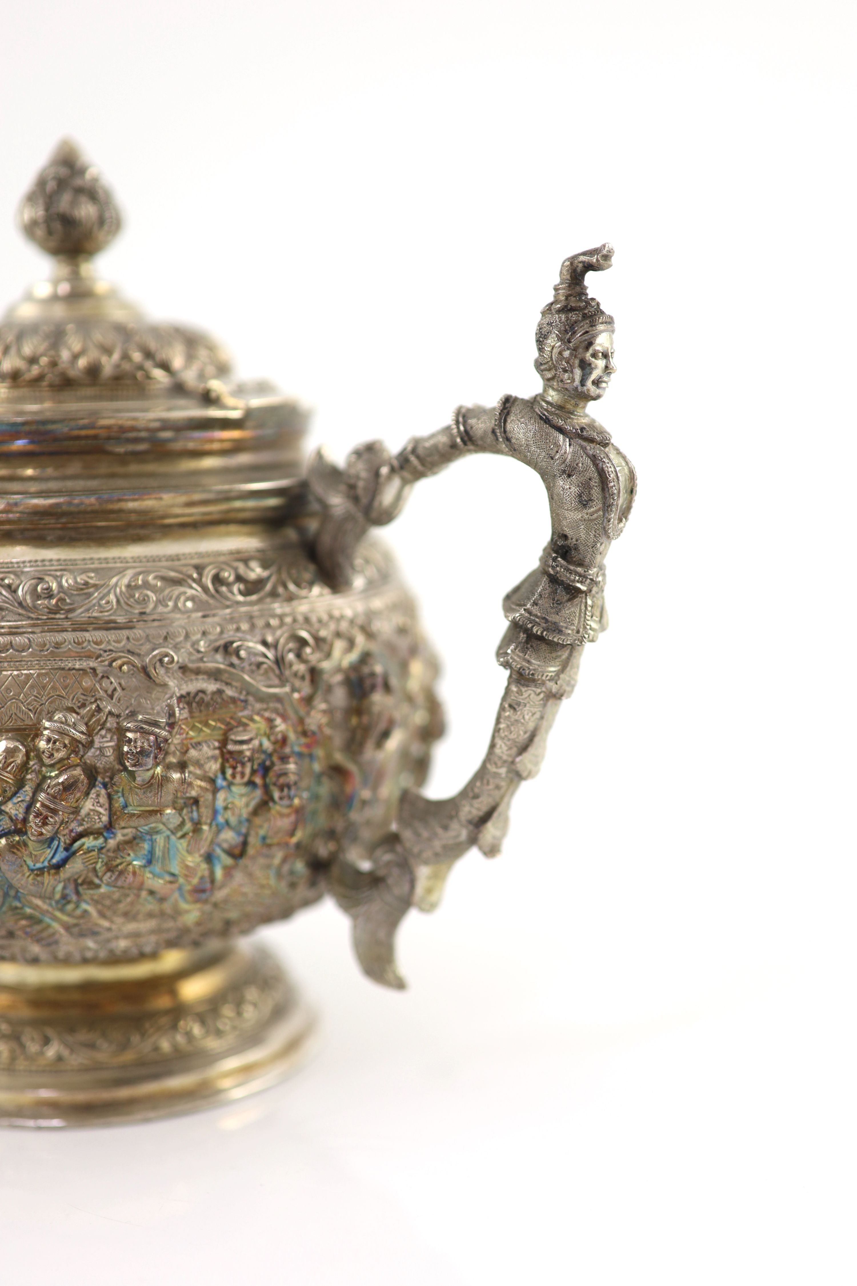 An impressive Burmese Sterling silver (950) three-piece tea service, with tray, cast with figures, teapot with cockerel spout and figural handle